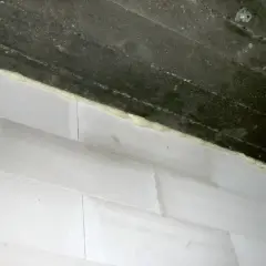 Piana montażowa wypełnia szczelinę między betonowym stropem a ścianą z białych pustaków. Idealne rozwiązanie, czym wypełnić dylatacje w ścianie.