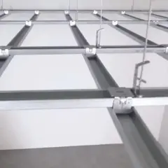 Sufit podwieszany krzyżowy z białymi panelami i metalową konstrukcją. Widać system profili, który tworzy siatkę, a nie pojedyncze belki.