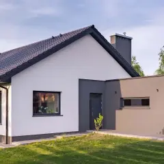 Nowoczesny dom z białymi i grafitowymi akcentami. Elewacja zewnętrzna prezentuje harmonijne połączenie kolorów, tworząc elegancki wygląd.