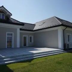 Nowoczesny dom z tarasem i schodami. Elegancki gzyms zdobi fasadę, podkreślając architekturę.