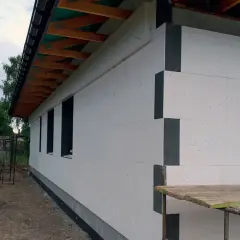 Budynek w trakcie budowy, ściany ocieplone styropianem. Widoczna instalacja odgromowa pod styropianem, przygotowana do dalszych prac.
