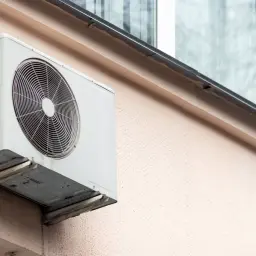 Montaż jednostki zewnętrznej klimatyzatora na elewacji budynku. Urządzenie zamontowane na wspornikach, gotowe do pracy.