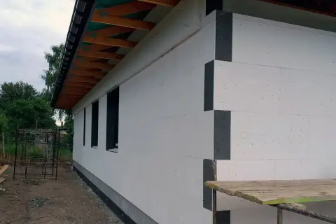 Budynek w trakcie budowy, ściany ocieplone styropianem. Widoczna instalacja odgromowa pod styropianem, przygotowana do dalszych prac.