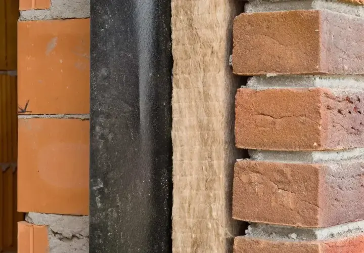 Warstwa izolacji z wełny mineralnej, która wpływa na niski współczynnik lambda, między czarną membraną a cegłą.