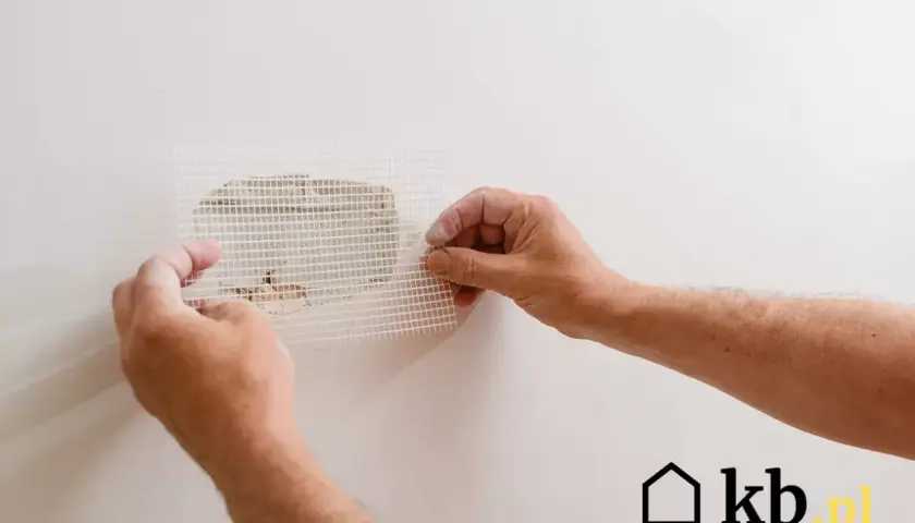 Ręce przykładają siatkę do dziur w ścianie. Świetny pomysł na zakrycie dziur w ścianie i naprawę ubytków.