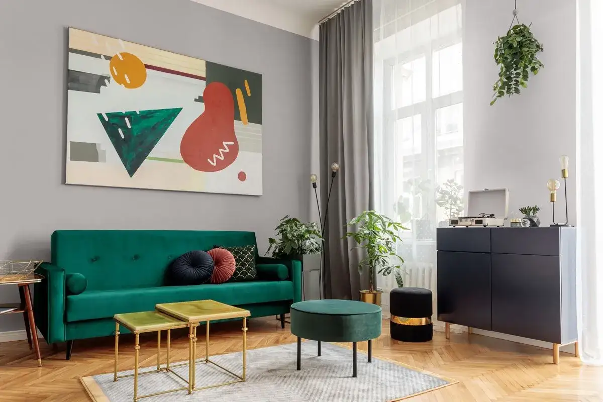 Nowoczesny salon z zieloną kanapą, stolikami i abstrakcyjnym obrazem. Czy pasek pod sufitem czy bez? W tym wnętrzu jest subtelnie.