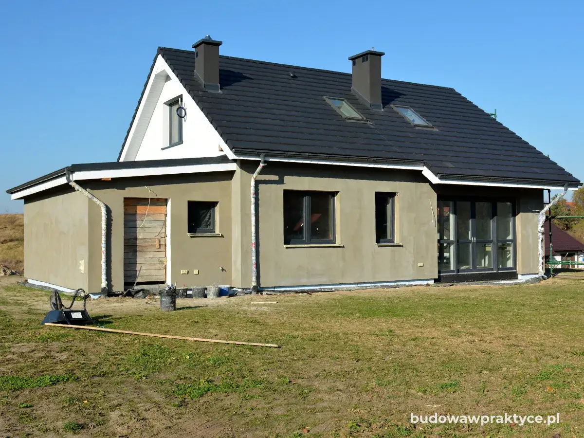 Dom w trakcie prac wykończeniowych, z widocznym tynkiem zewnętrznym. Zastanawiasz się, ile kosztuje ocieplenie domu?